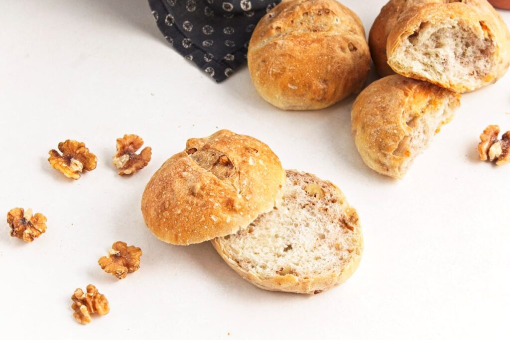 Crusty walnut loaves on a white surface.