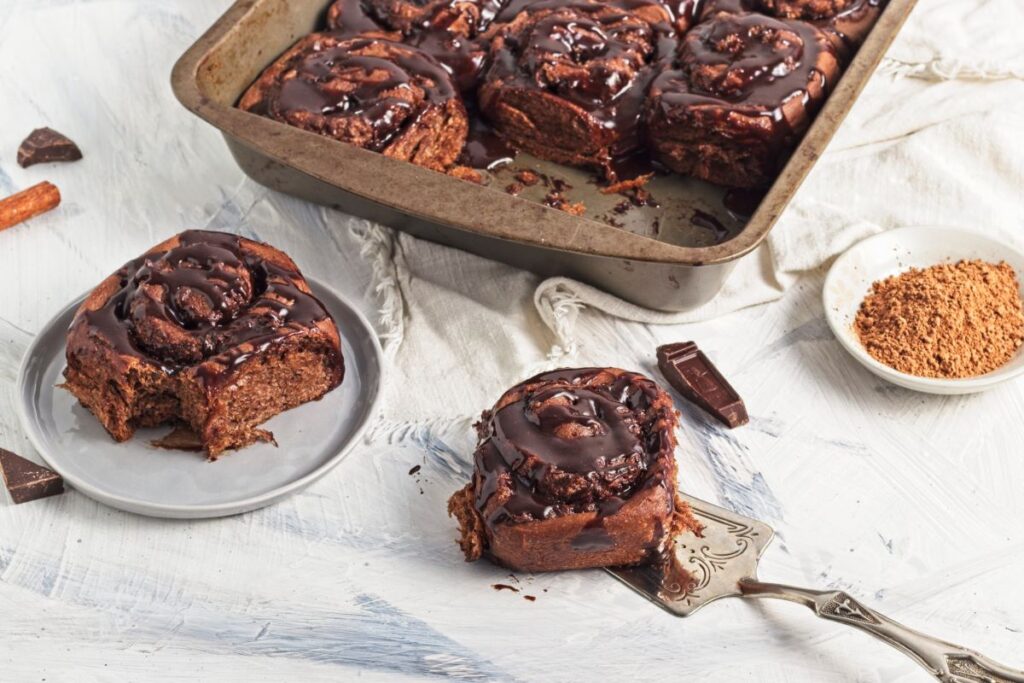 Chocolate Cinnamon Rolls in a baking dish with one on a spatula.