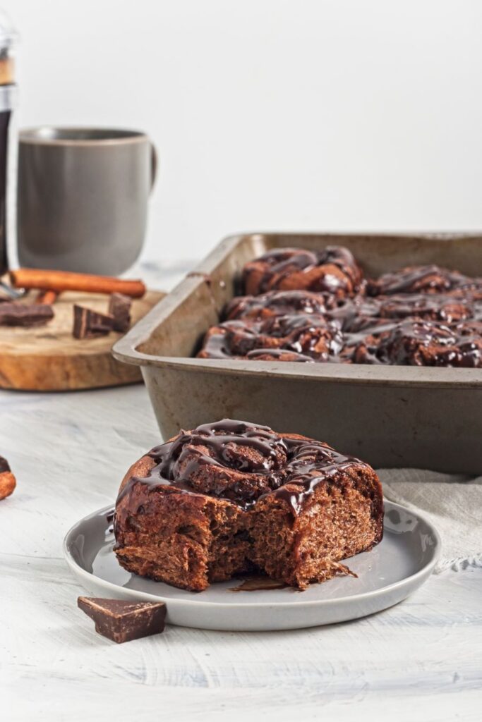 Chocolate Cinnamon Rolls in a baking dish with one on a plate.