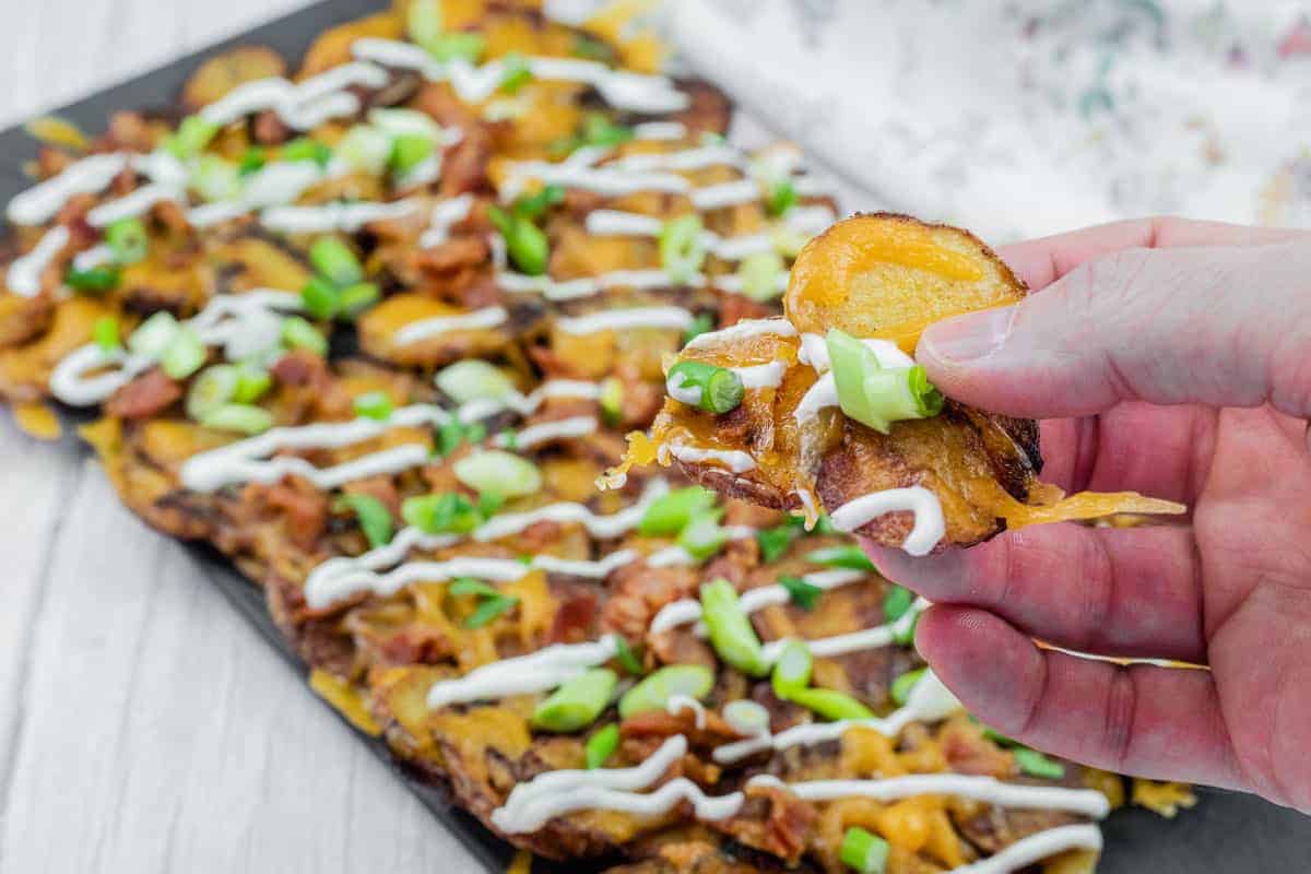Tray of Irish nachos topped with green onions, bacon, cheese, and drizzled with sour cream.