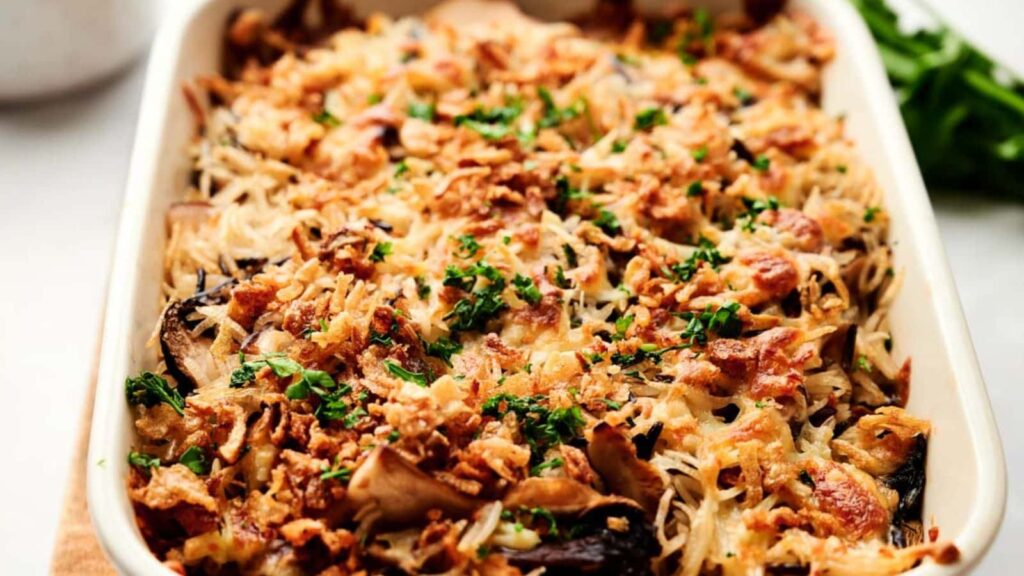 A baked casserole topped with crispy fried onions and chopped parsley, featuring a golden-brown surface and visible shredded cheese.