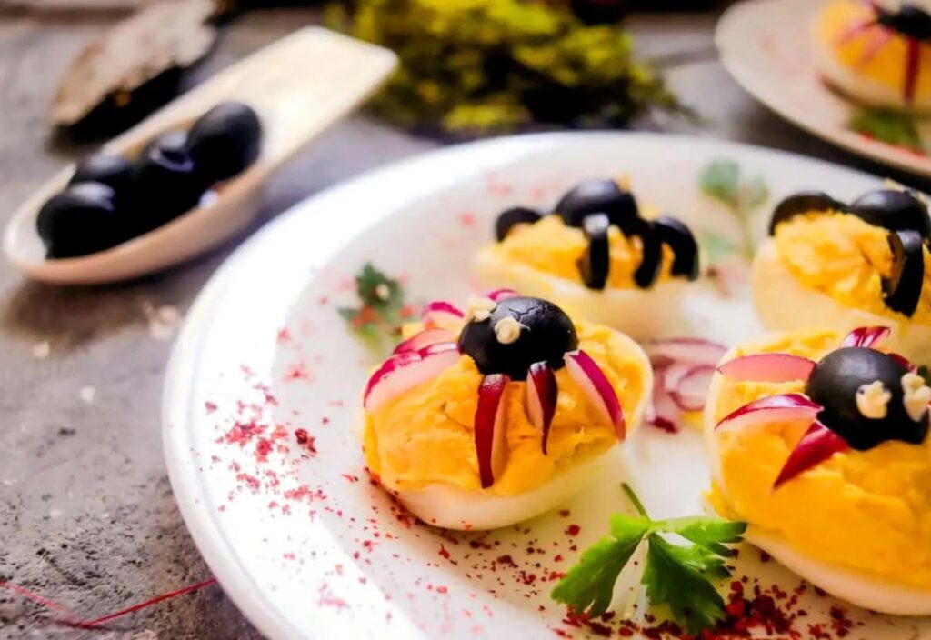 Deviled eggs with black olive spiders.