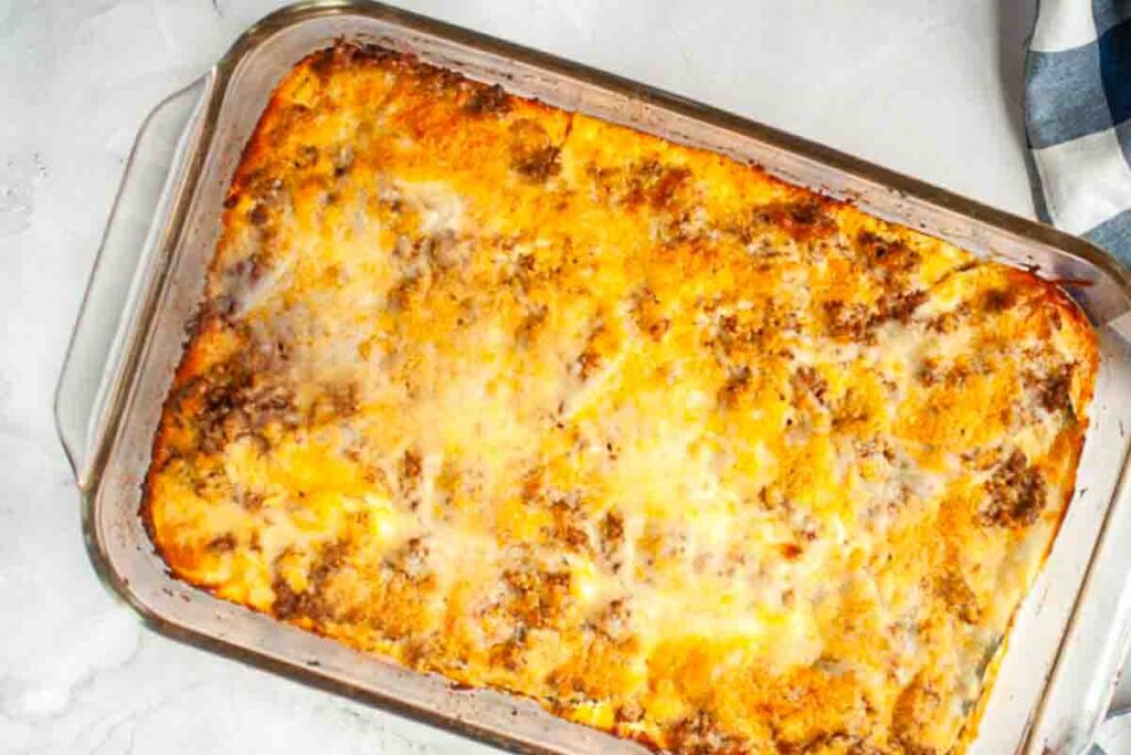 A baked casserole with a golden brown, melted cheese topping and visible ground meat in a rectangular glass dish.