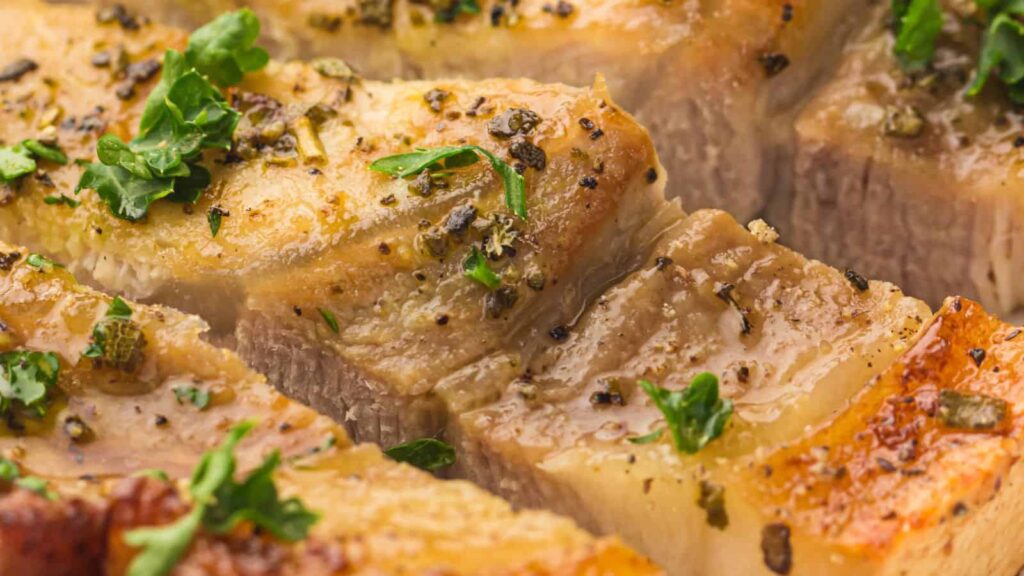Close-up of seasoned, cooked meat garnished with chopped herbs.