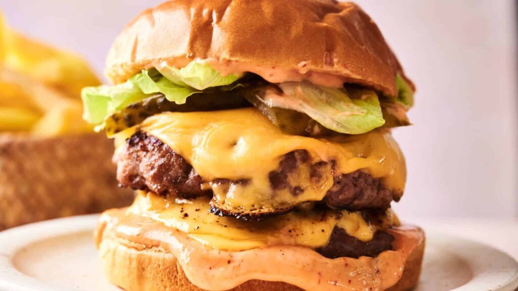 A hamburger with cheese and lettuce on it.