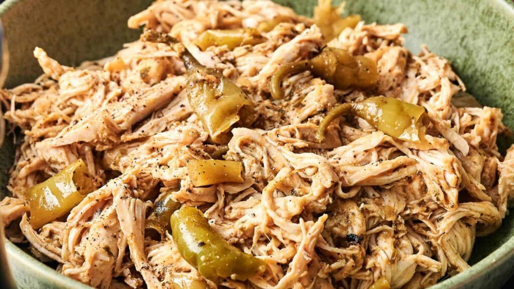 A bowl of shredded chicken mixed with sliced green peppers and seasoned with black pepper.