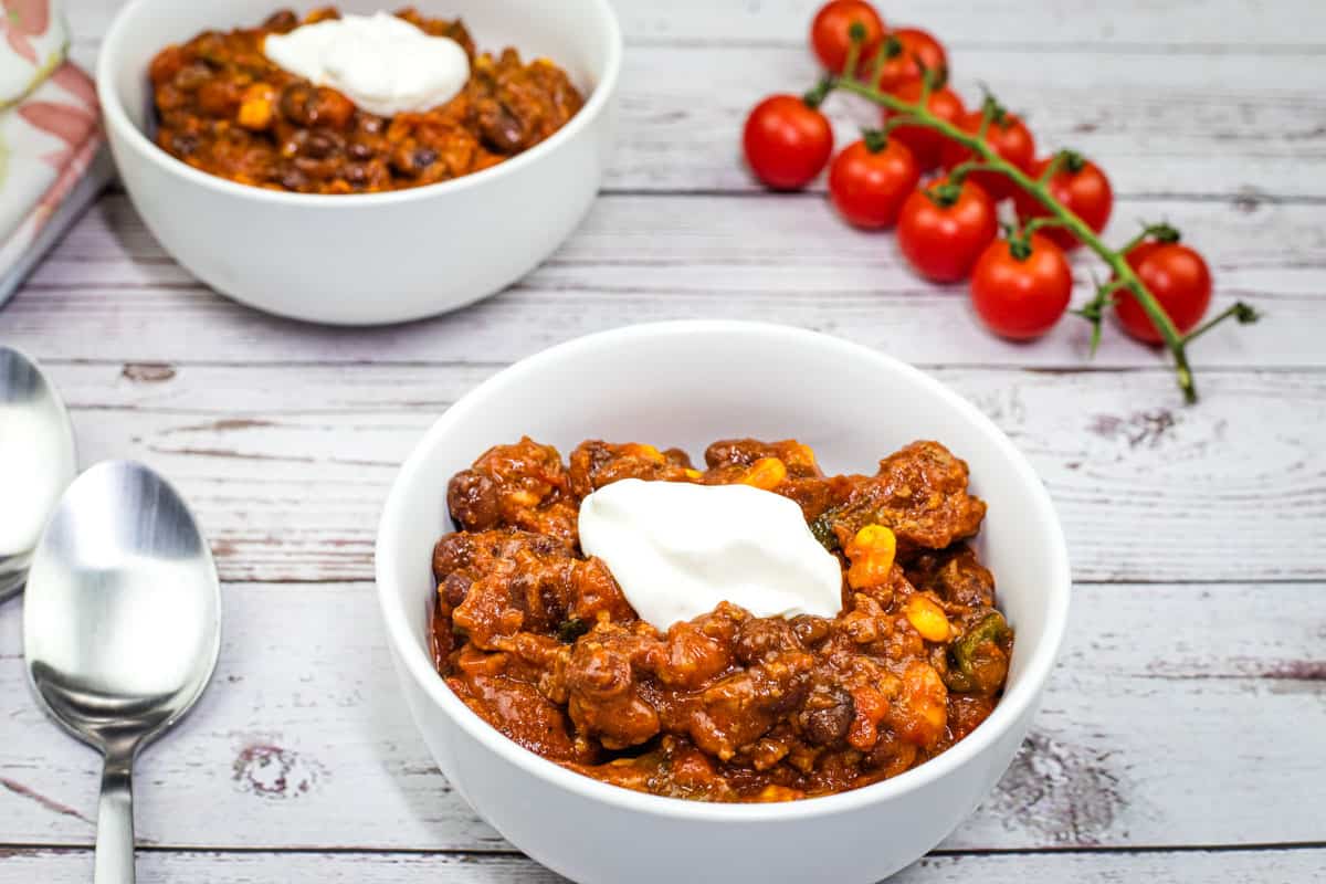 Two bowls of Slow Cooker Southwestern Chili with cherry tomatoes and spoon on the side.