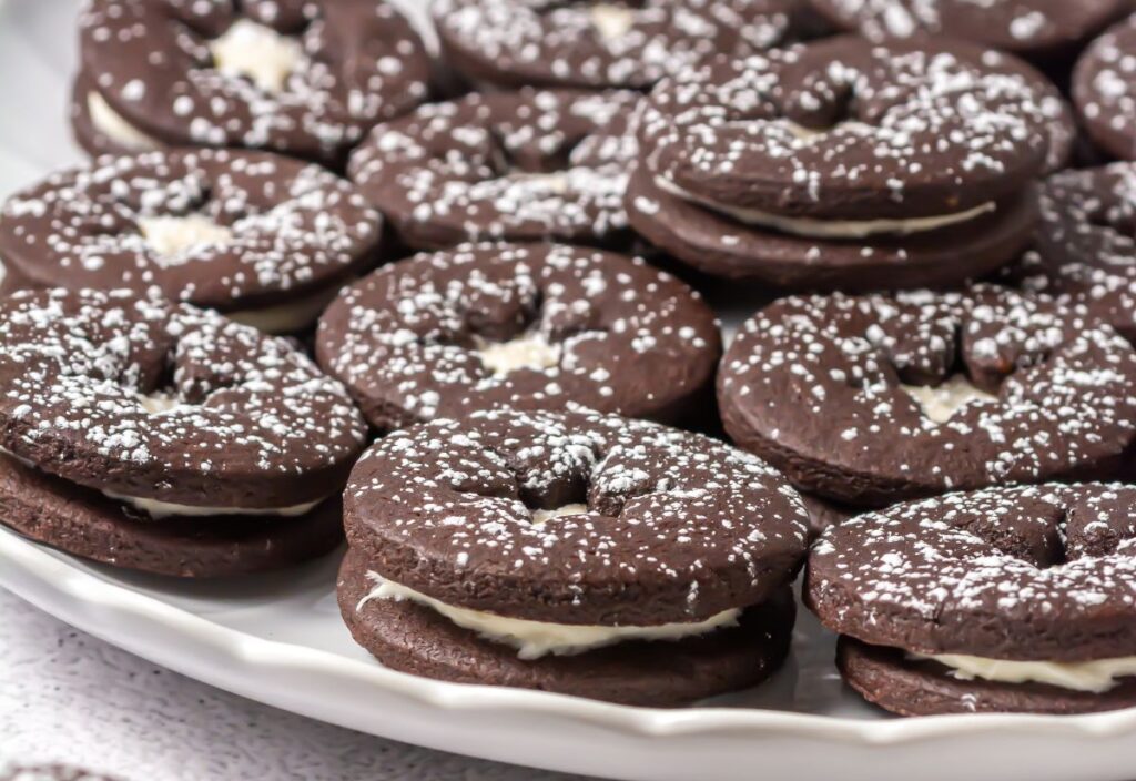 Chocolate linzer cookies dusted with powdered sugar on a plate