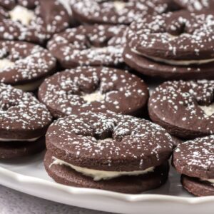 Chocolate linzer cookies dusted with powdered sugar on a plate