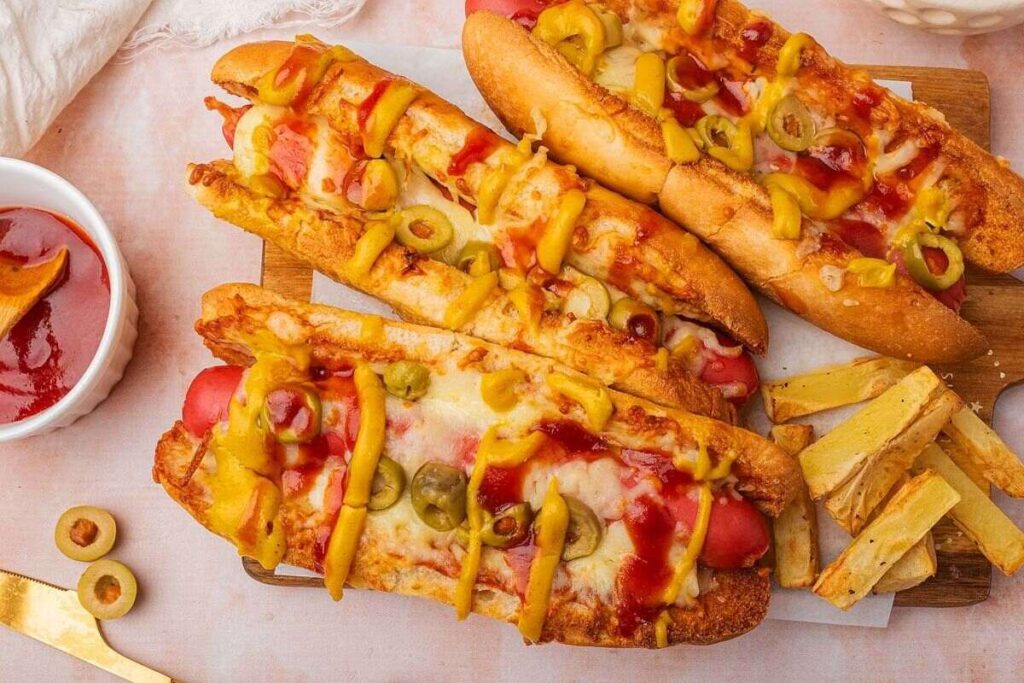 Hot dogs turn pizza-flavored with cheese, olives, mustard, and ketchup, paired with fries.
