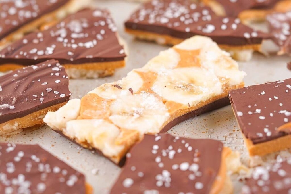 Chocolate banana bark pieces with a sprinkle of salt, served with banana slices.