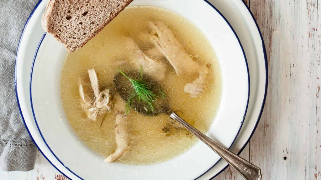 white bowl with chicken soup and a spoon
