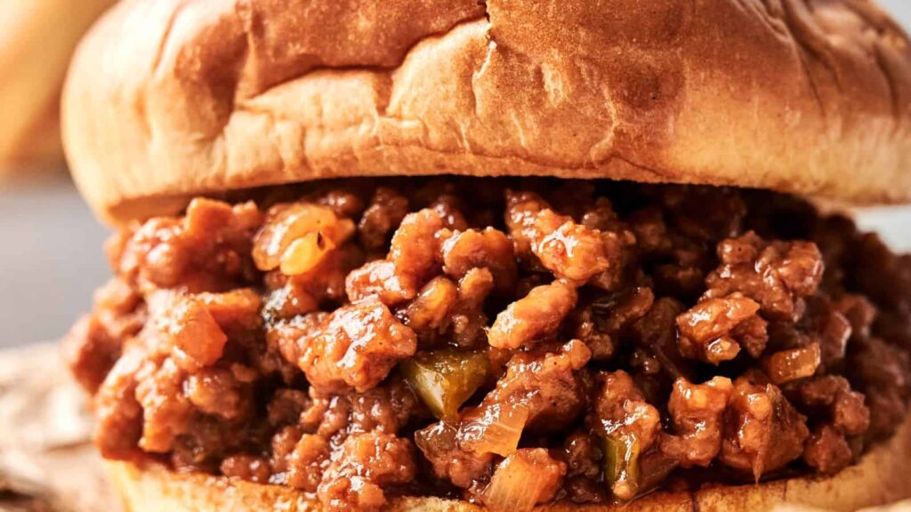 Close-up of a sloppy joe sandwich with seasoned ground beef and sauce on a toasted bun.