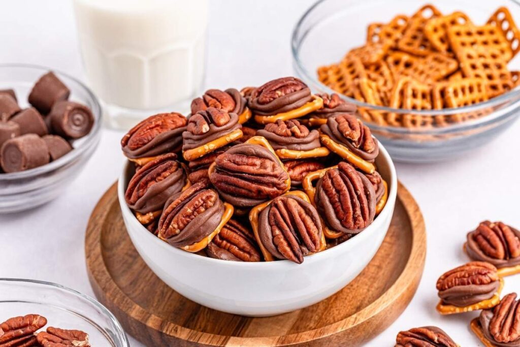 A white bowl of 3-ingredient pretzel turtle bites sits on a wooden tray.