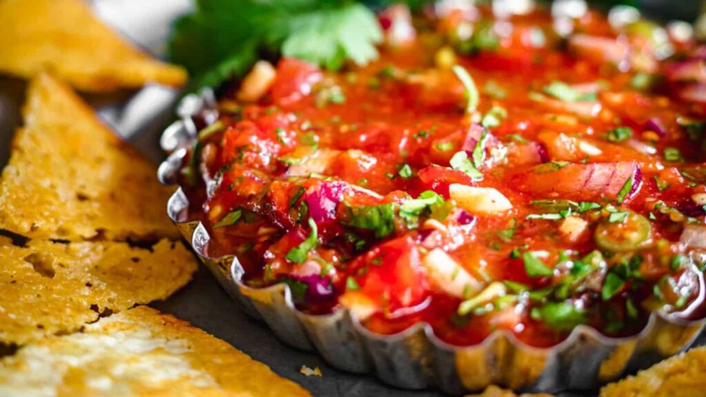 Salsa in a container with chips around it.