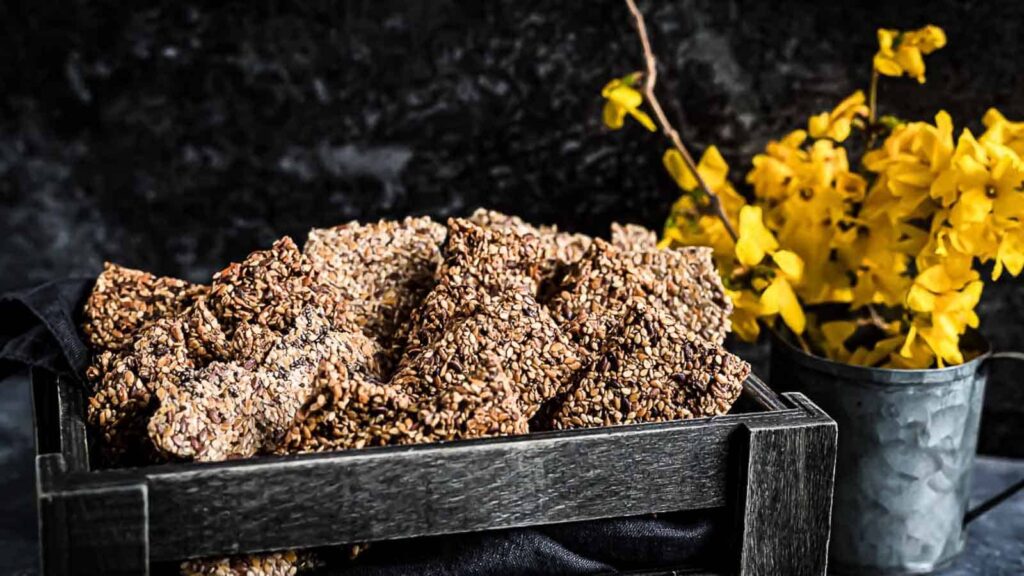Raw Seed Crackers Bread inside dark brown wooden basket.