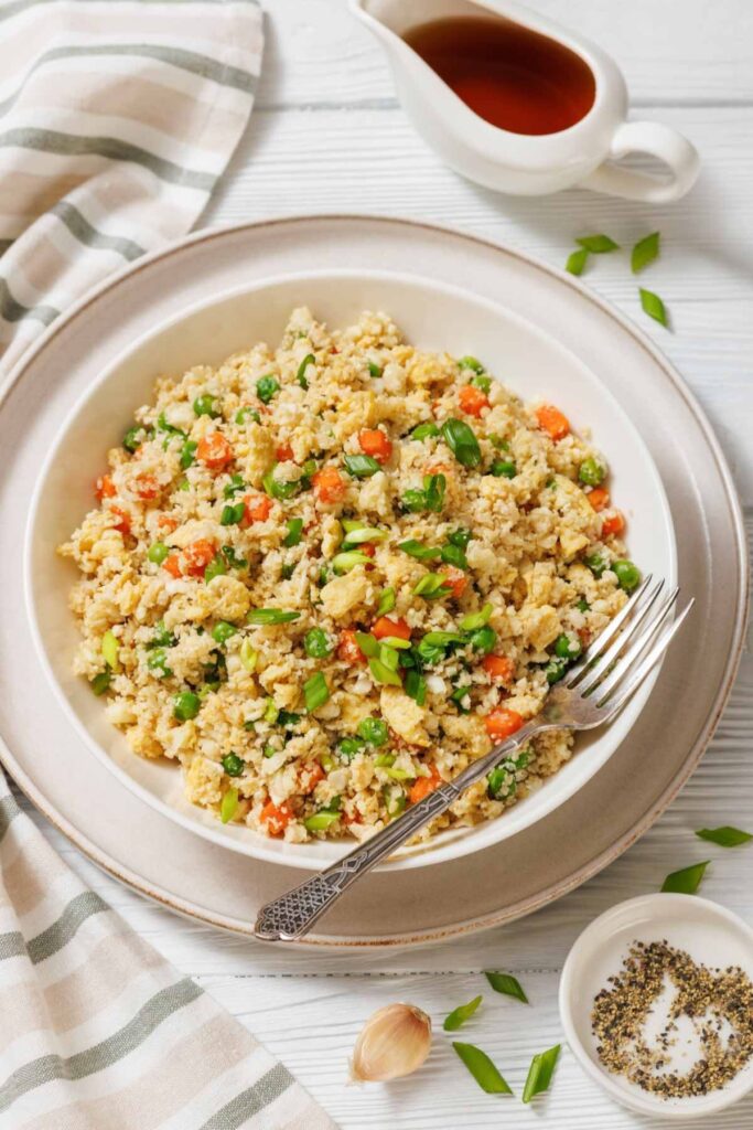 Finished cauliflower fried rice in a skillet with vegetables and scrambled eggs.