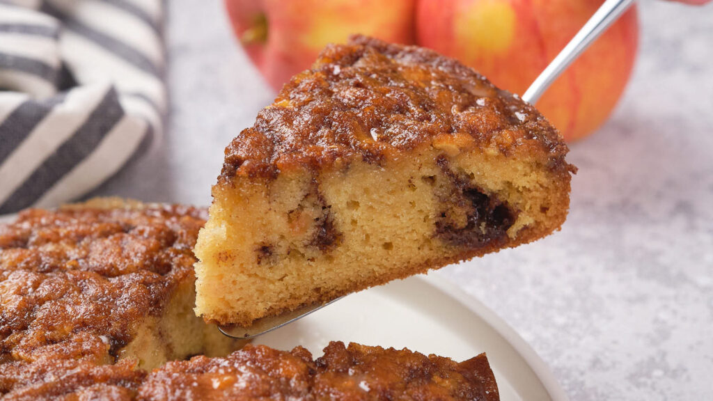 A spatula lifting up a slice of apple cinnamon cake.