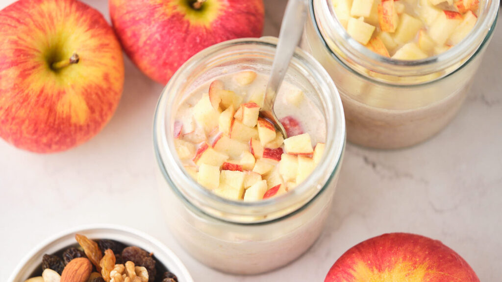 A jar of apple cinnamon oats on a white surface.