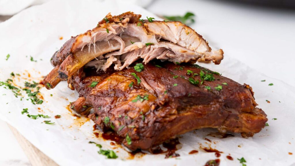 Baby back ribs garnished and served on a white plate.