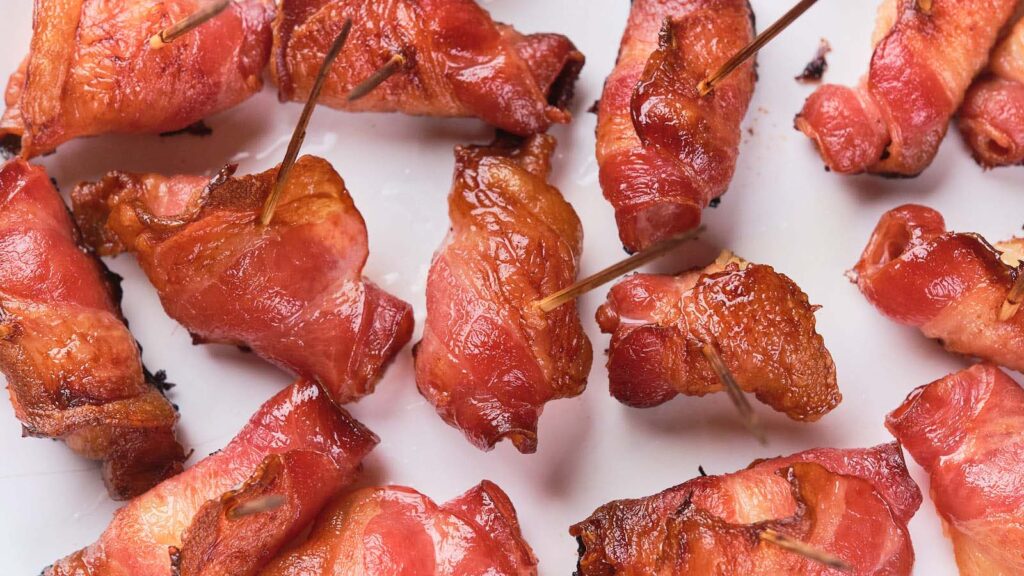 A plate with several pieces of bacon arranged neatly on a white dish.
