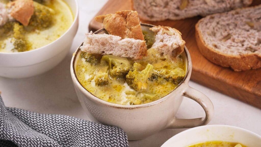 A bowl of broccoli cheddar soup served with bread.