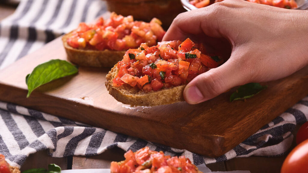 A person is holding a bruschetta al pomodoro.