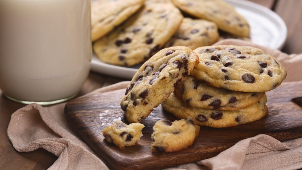 Chocolate chip cookies resting on a wooden board,