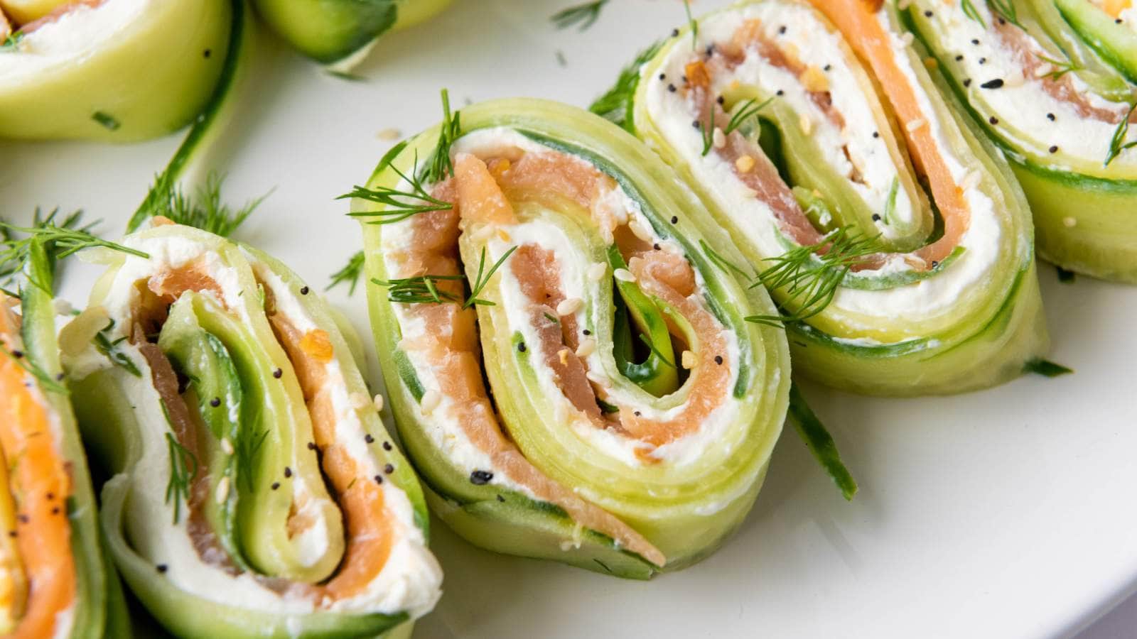 Slices of cucumber appetizers filled with cream cheese, smoked salmon, and dill, garnished with additional dill.