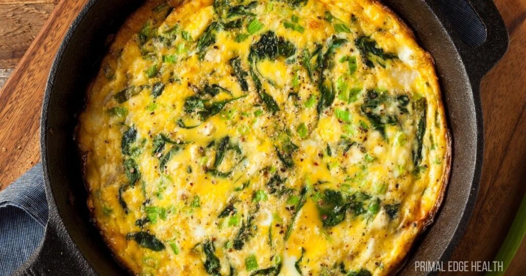 Cooked fritata with spinach and feta on a skillet.