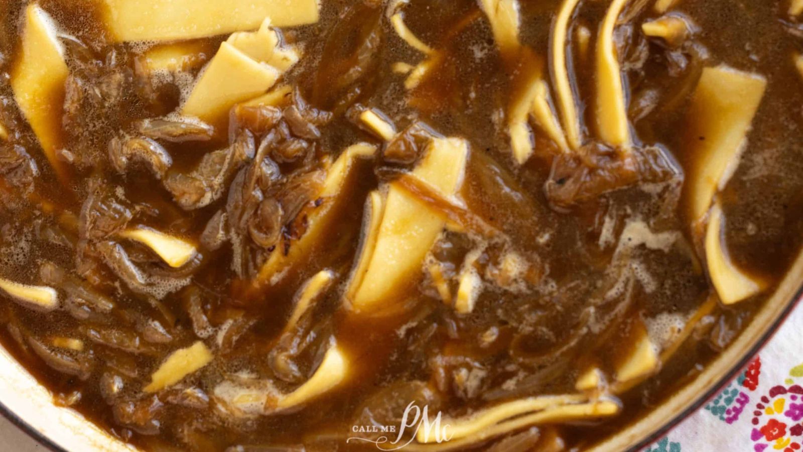 A pot of soup with noodles and meat in it.