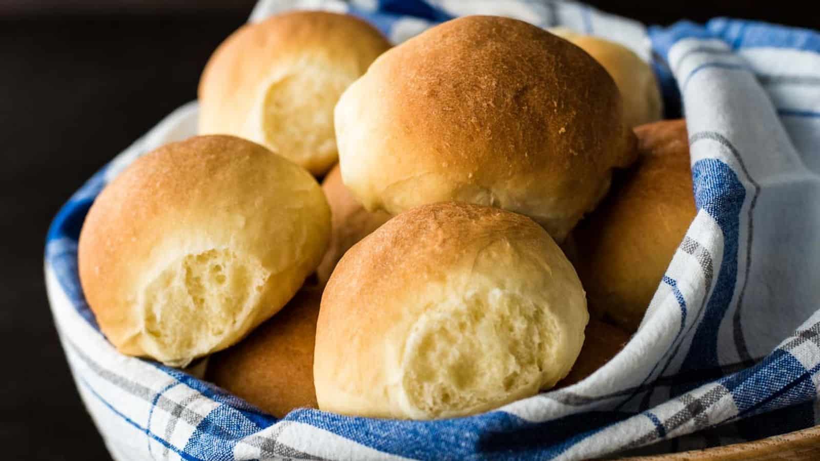 Brioche rolls on a baking sheet on top of a towel.