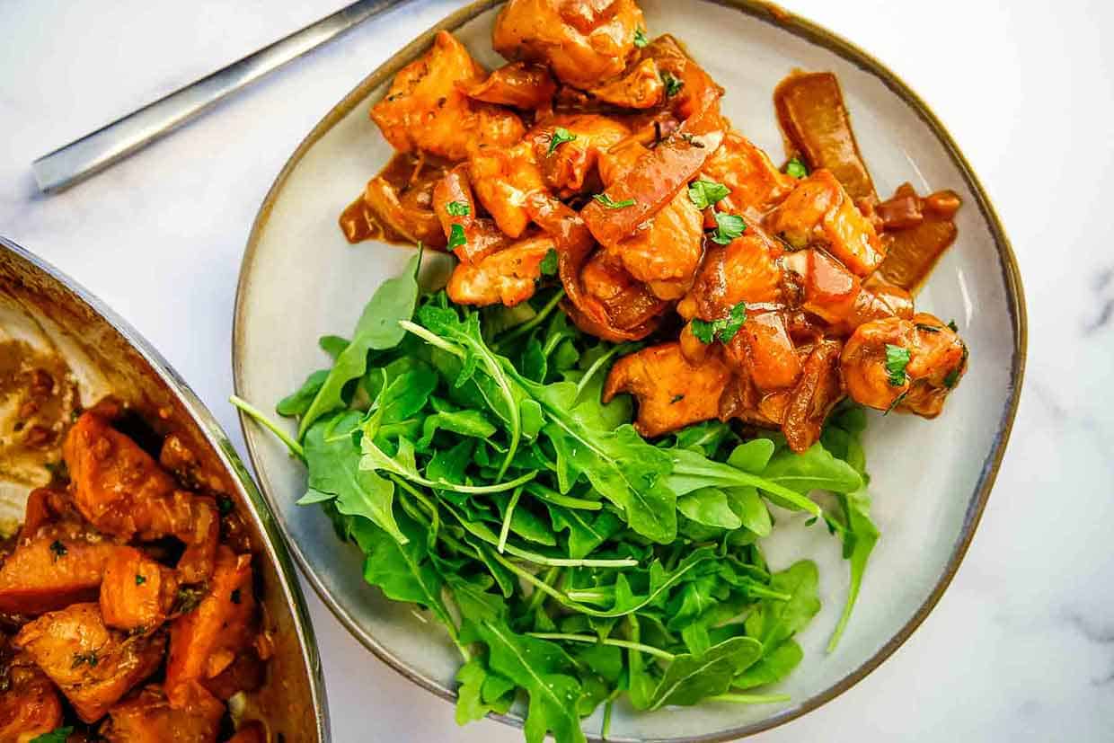 A serving of creamy balsamic chicken skillet next to a serving of green salad.