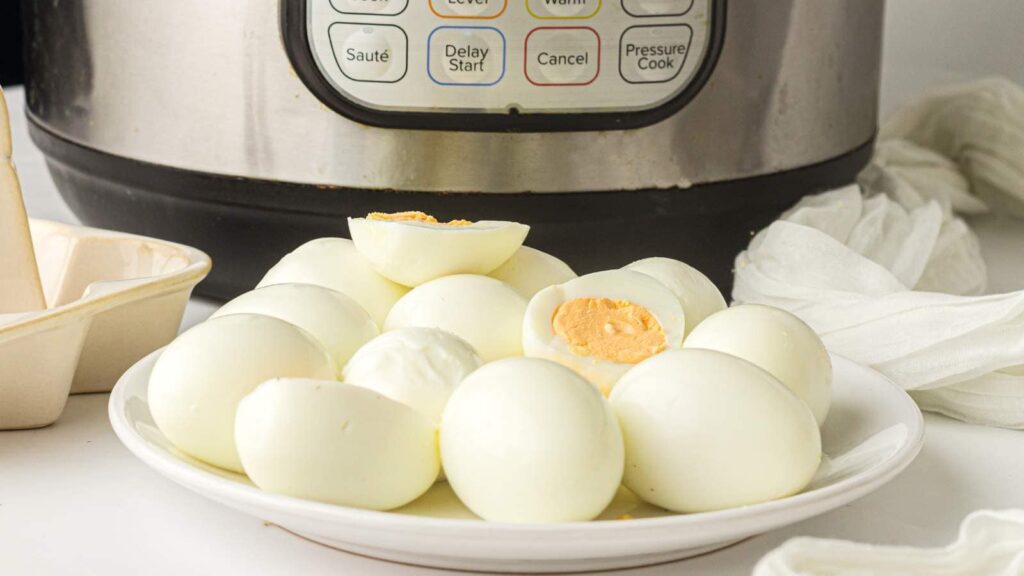 Boiled eggs on a white plate with an Instant Pot behind it.