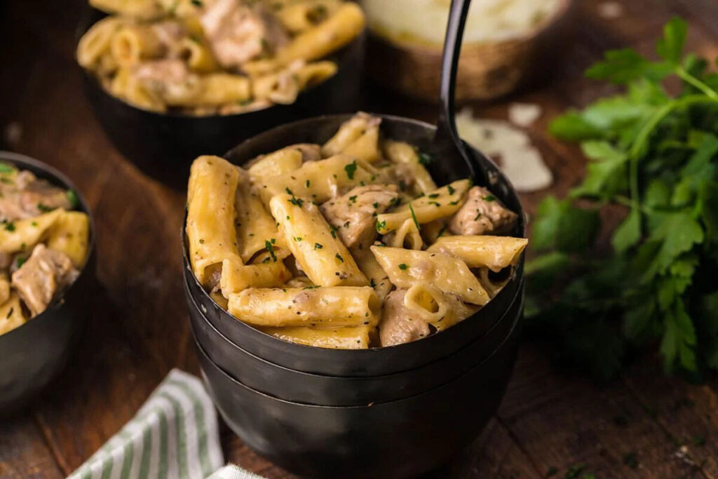 Penne pasta with chicken in black bowls.