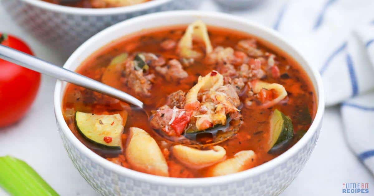 Minestrone Soup with Sausage in white bowl with spoonful.