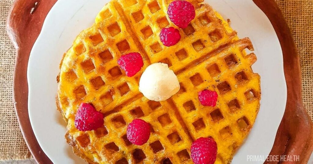A piece of waffle garnished wit raspberries.