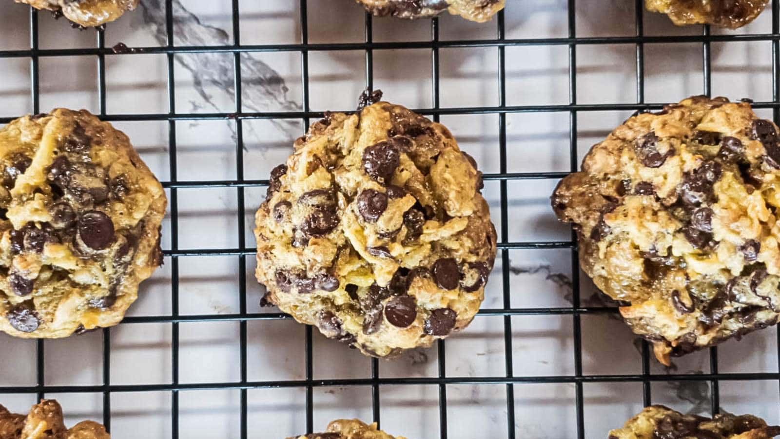 Magic cookies cooling on a black wire rack over a marble surface.