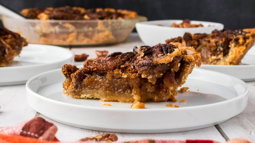 A white plate with a slice of pecan pie on it.