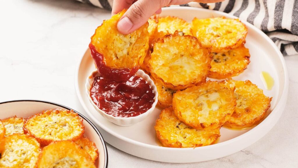 Pickle chips with a ramekin of sauce on a white plate.