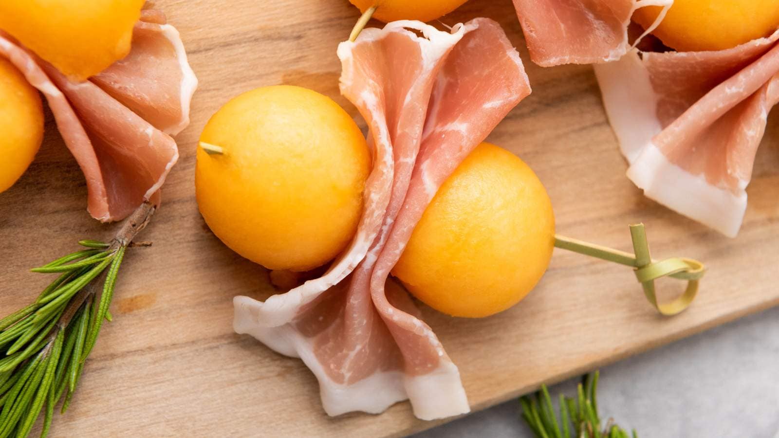 Slices of prosciutto e melone wrapped around cantaloupe balls, skewered.