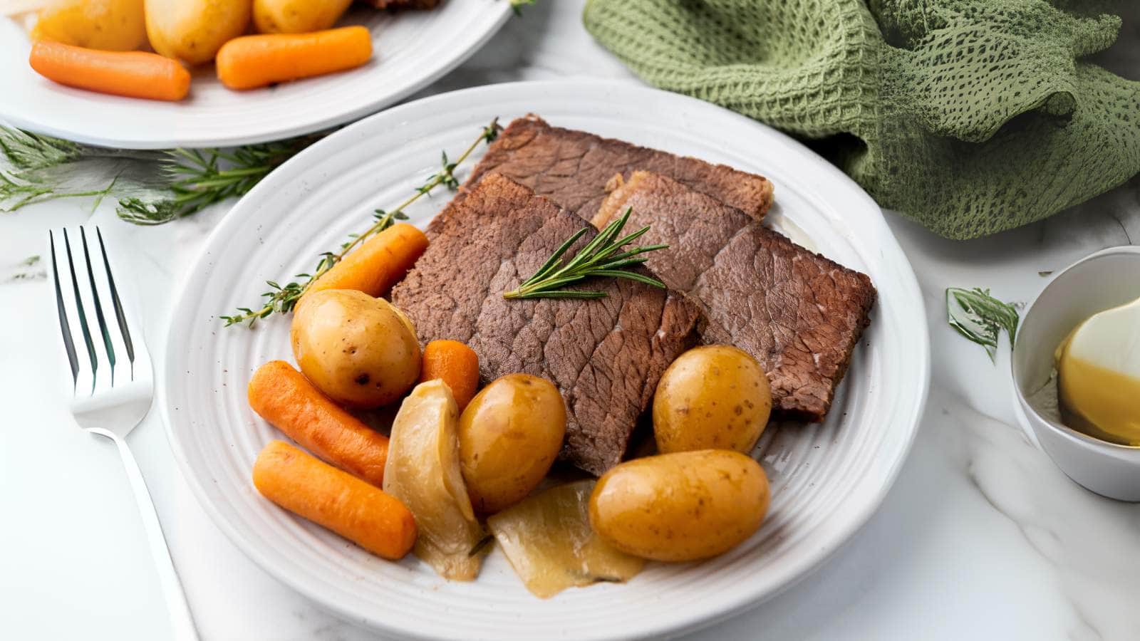 A plate with sliced rump roast, baby potatoes, carrots, and onions, garnished with a sprig of rosemary.