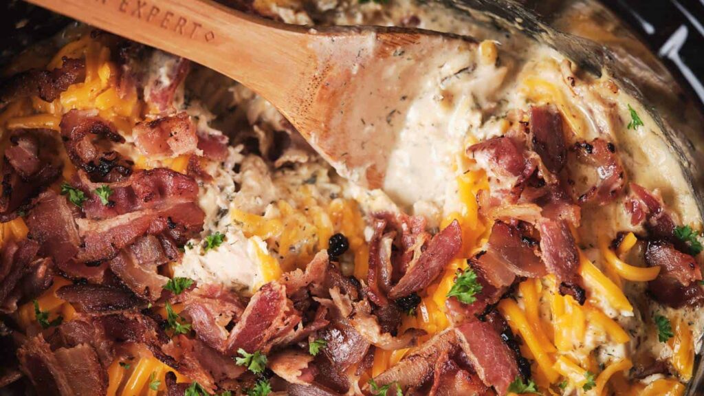 An upclose shot of cheesy crack chicken with a wooden spoon.