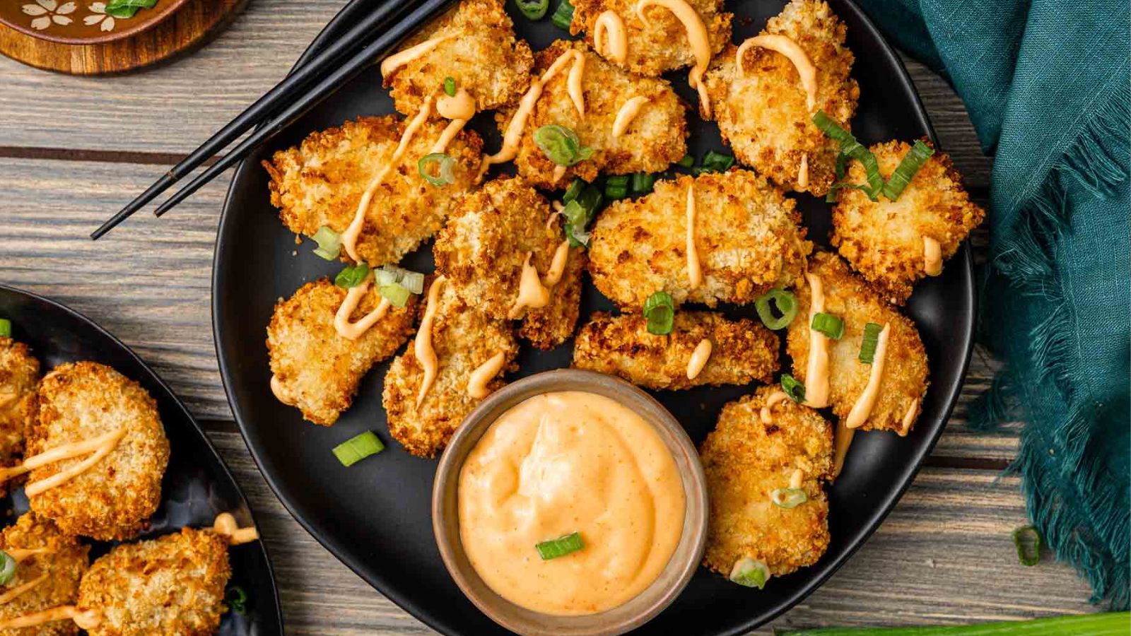 Air fryer bang bang chicken bites coated in creamy spicy sauce on a serving plate.
