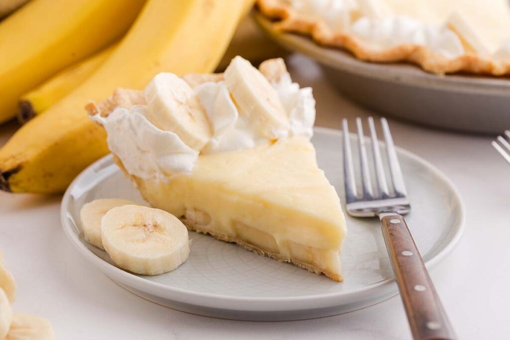A slice of banana cream pie with whipped cream and fresh banana.