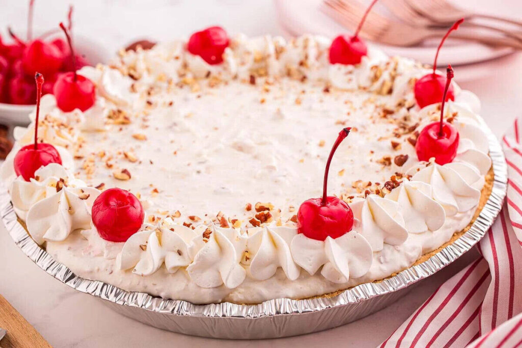 A creamy pie topped with whipped cream, cherries, and nuts.
