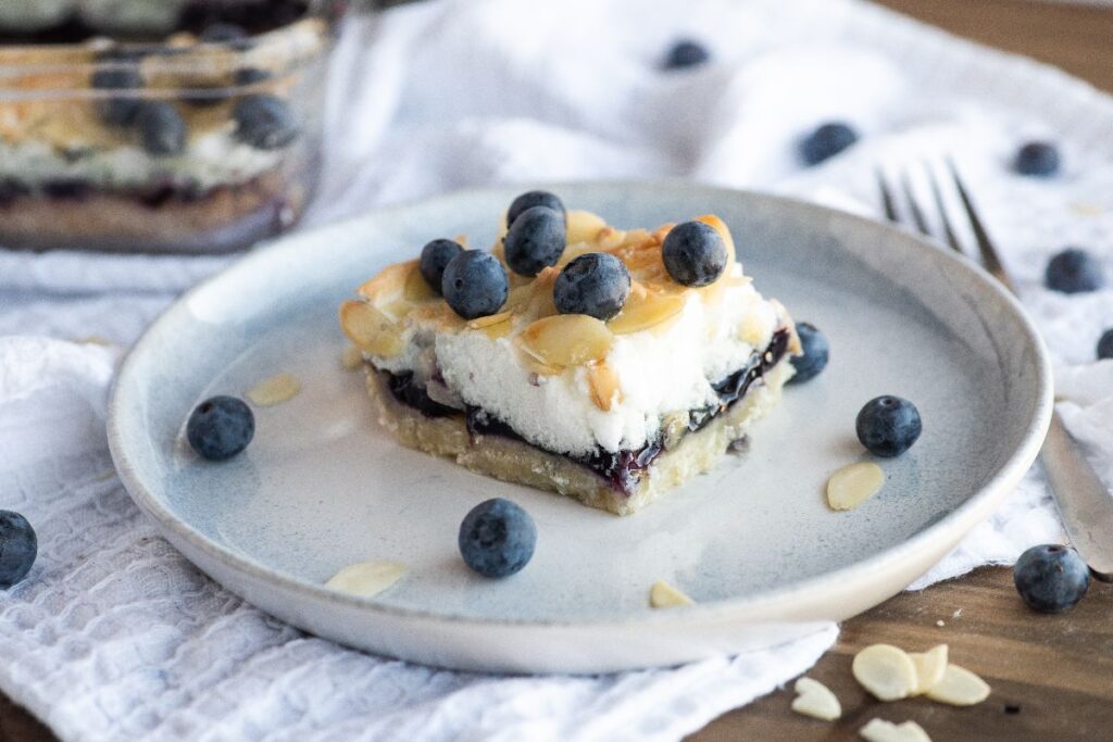 Blueberry and almond cookie bars topped with fresh blueberries and almond slices.