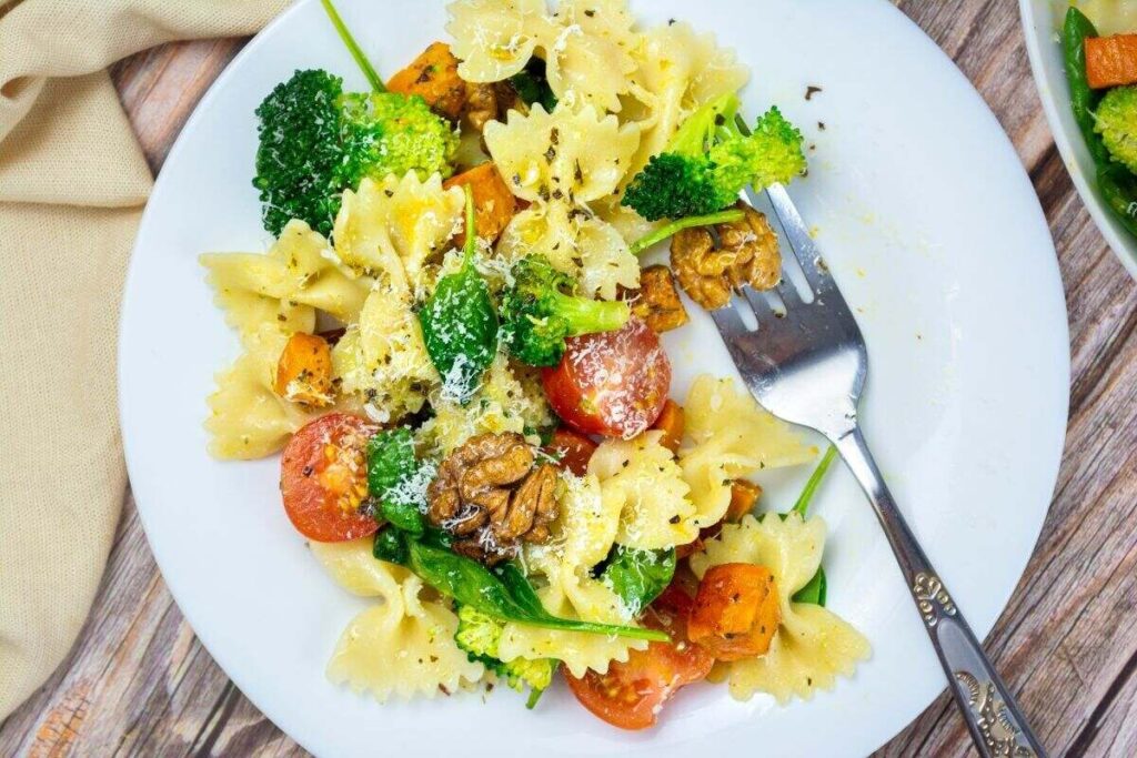 Farfalle pasta with broccoli, cherry tomatoes, walnuts, and cheese for a colorful pasta salad twist.