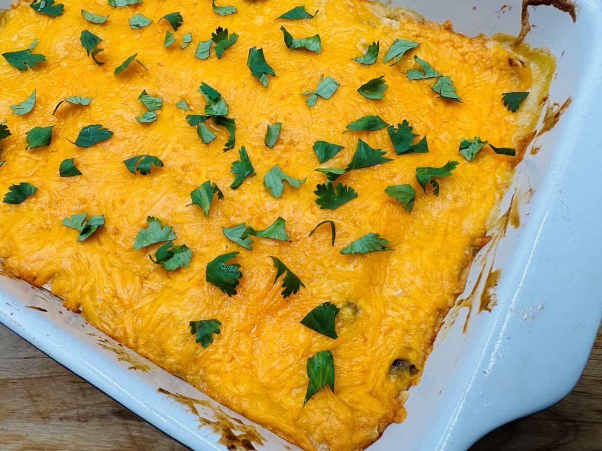 A baked casserole topped with melted cheese and garnished with fresh cilantro in a white rectangular dish.
