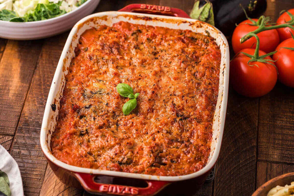A baked dish of lasagna in a red casserole dish.